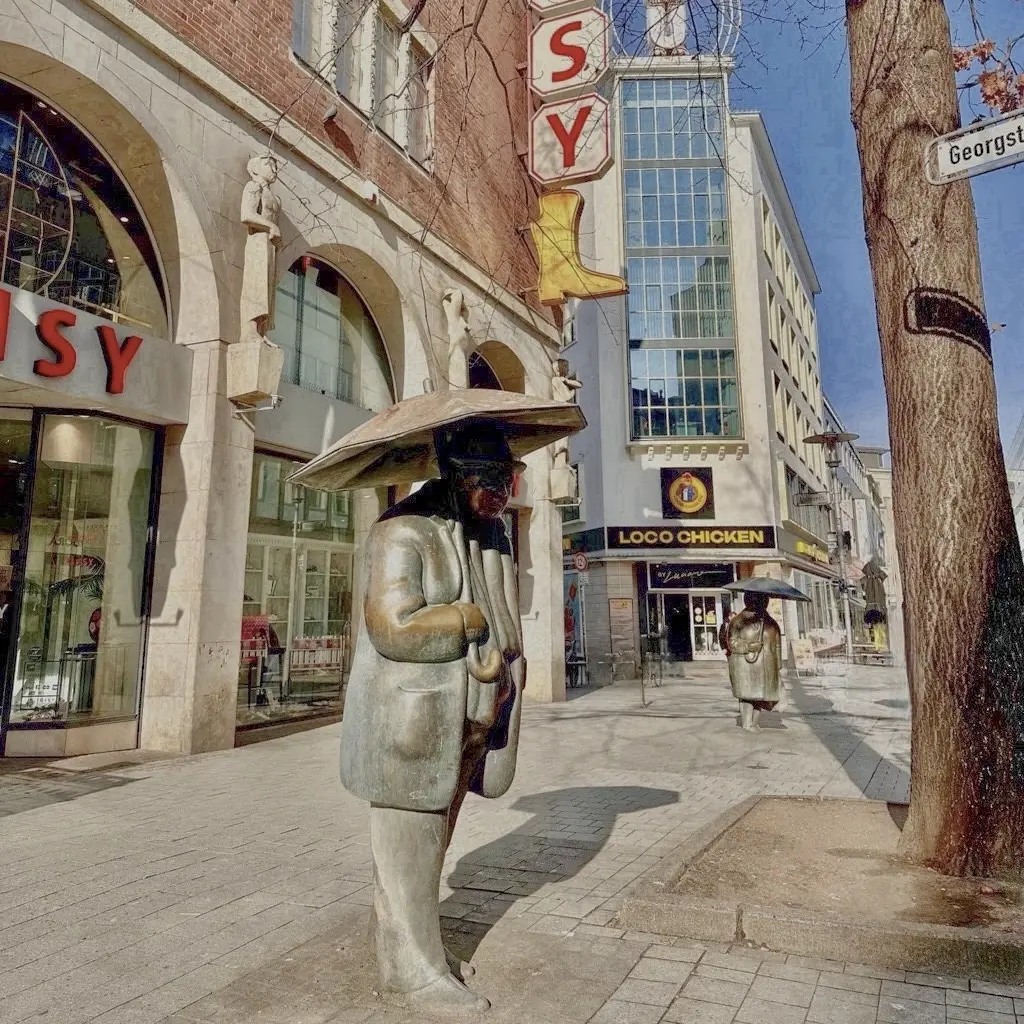 Blick in die Andreaestraße in Hannover-Mitte mit der Skulptur eines Mannes mit Regenschirm, im Hintergrund das Gebäude Andreaestraße 2